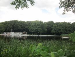 Naturteich mit Gebäude im Hintergrund